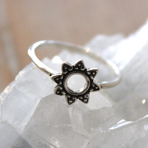 Silver ring with a sun design on a white stone background