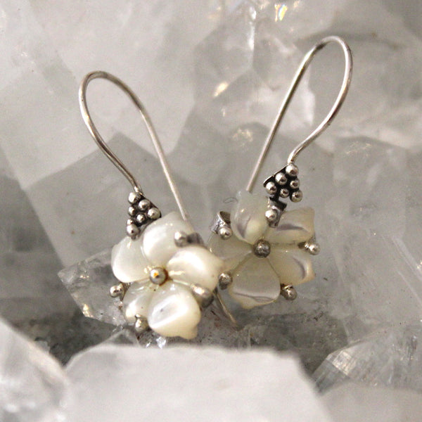 Silver earrings with pearl-like beads on a textured gray background