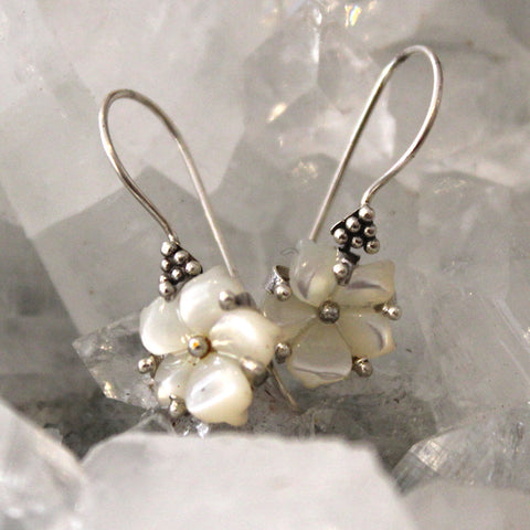 Silver earrings with pearl-like beads on a textured gray background