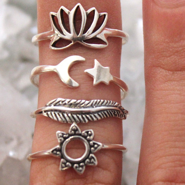 Set of silver rings with various designs on a finger against a neutral background