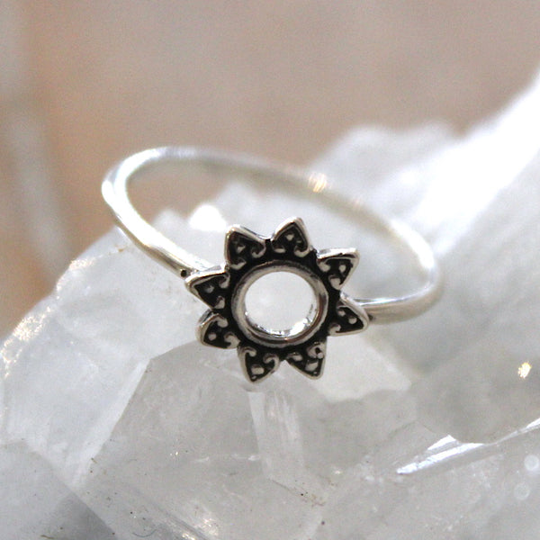 Silver ring with a sun design on a white stone background